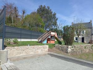 a house with a stone wall and a building at Gite Ti Maen in Sulniac