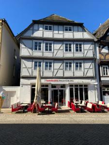 a large white building with tables and an umbrella at Marktplatzapartment 3 in Höxter
