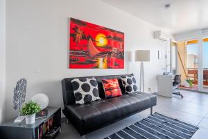 a living room with a black leather couch and a painting at SuiteOn7th Vilamoura Panoramic Sunset View Balcony Suite in Quarteira