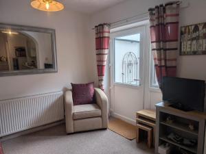 a living room with a chair and a mirror and a window at Sandham Hall Cottage in Sandown