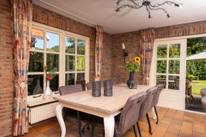 a dining room with a table and chairs and windows at Boomgaard | 4-16 pers. in Losser