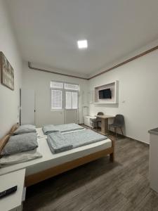 a white bedroom with a bed and a desk at Apartman Milanović in Pribojska Banja