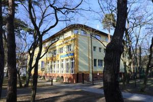 a yellow building with trees in front of it at Floryda in Jurata