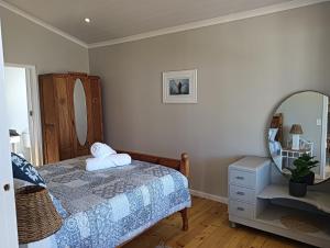 a bedroom with a bed and a mirror at Beach Walk by Salted Fynbos Staying in Pearly Beach