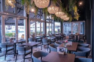 a restaurant with tables and chairs and chandeliers at Hampshire Hotel – Voncken Valkenburg in Valkenburg