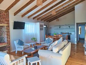 a living room with white furniture and a brick wall at Beach Walk by Salted Fynbos Staying in Pearly Beach