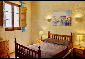 a bedroom with a bed and two lamps and a window at Shamrock House in Qala