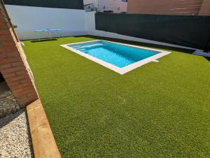 a backyard with a pool and green grass at VILLA Pinemar & Relax in Pineda de Mar