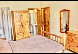 a bedroom with a bed and wooden cabinets and a sink at Shamrock House in Qala