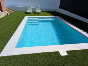 a swimming pool with two chairs in a yard at VILLA Pinemar & Relax in Pineda de Mar
