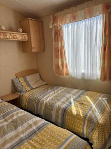 a small room with two beds and a window at Bardsey View Holiday Park Nr New Quay in Llanarth