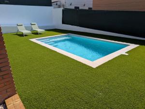 a swimming pool with two chairs on the grass at VILLA Pinemar & Relax in Pineda de Mar