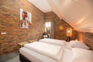 a bedroom with two beds and a brick wall at De Regenboog in Losser