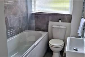 a bathroom with a toilet and a tub and a sink at K Suites - Station Road 2 in Hinckley