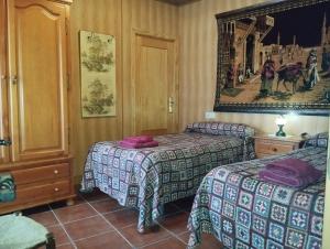 a hotel room with two beds and a picture on the wall at Casa Rural Cueva El Sauce in Pegalajar