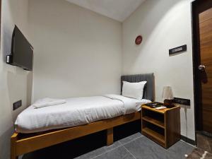 a bedroom with a bed and a tv and a table at Hotel Navas Inn- Pure Veg, Kolhapur in Kolhapur