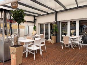 a restaurant with white tables and chairs and windows at New Corner in Niechorze