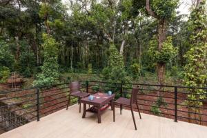 a table and two chairs on a deck with trees at Tusker Trails - A LuxUnlock Private Retreat in Suntikoppa