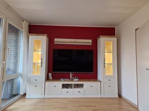 a living room with a flat screen tv on a red wall at Nordseeperle in Hooksiel