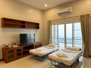 a room with two beds and a tv and a balcony at Tsuya Hill Private Mountain View Villa, Chiang Rai in Mae Chan