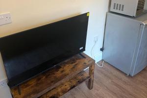 a flat screen tv sitting on a wooden table next to a refrigerator at Apartment Sleeps 2 in Leigh