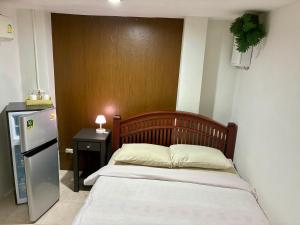 a small bedroom with a bed and a refrigerator at Farang house in Pattaya