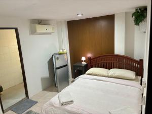 a small bedroom with a bed and a refrigerator at Farang house in Pattaya