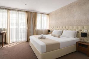 a bedroom with a large white bed and windows at Alexandar Square Boutique Hotel in Skopje +57 photos