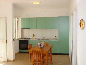 a kitchen with green cabinets and a table and chairs at Residence la Chimera in Villasimius