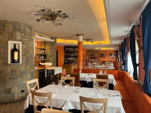 a restaurant with white tables and chairs and a bar at Hotel La Pastorella in Livigno
