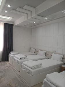 a white room with three beds in it at Safo Hotel Turkestan in Türkistan