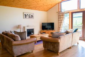 a living room with two couches and a tv at Plum Tree Lodge in Errol
