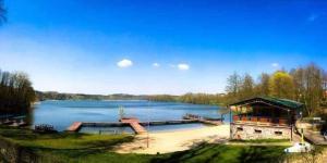 a large lake with a building and a dock at Domek nad jeziorem in Górzno
