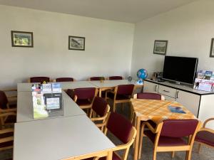 a waiting room with tables and chairs and a tv at Nr 6 Camping Pod mit Terrasse und Seeblick in Langenbernsdorf