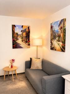 ein Wohnzimmer mit einer Couch und drei Gemälden an der Wand in der Unterkunft Saint Michael Boutique & Garni Hotel Trnava in Trnava