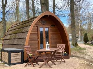 a small wooden cabin with a table and two chairs at Nr 6 Camping Pod mit Terrasse und Seeblick in Langenbernsdorf