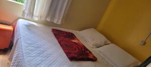 a bedroom with a bed with white sheets and a red pillow at Joy Hostel in Salvador