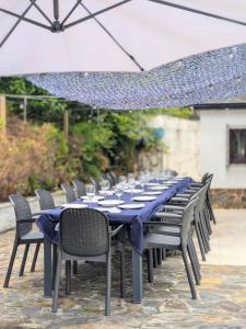 a long table with chairs and an umbrella at Finca Segade in A Estrada