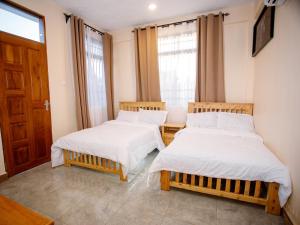 two beds in a room with two windows at Kili Tanzania in Moshi