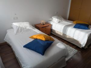 two beds with yellow and blue pillows in a room at Quarportugal in São Martinho do Porto