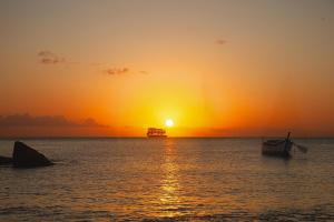 a boat in the ocean with a sunset in the background at LA DILETTANTE - Maison Créole de 130m2 - Clim - Tout à Pied in Terre-de-Bas