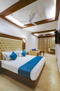 a bedroom with a large bed with blue pillows at Hotel The Metropolis Tourist Near Connaught Place And Ramakrishna Ashram Marg Metro Station in New Delhi +76 photos