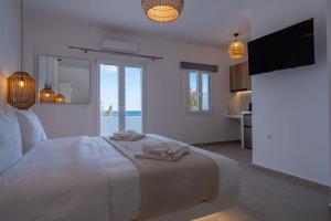 a white bedroom with a bed with a view of the ocean at Aqua Cozy Suites in Perissa