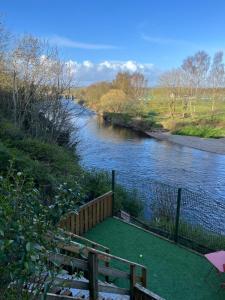 a view of a river with a bench next to a fence at Hallow Cottage in Newtownstewart