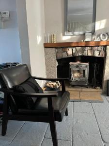 a leather chair in a living room with a fireplace at Hallow Cottage in Newtownstewart