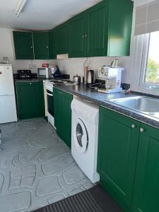 a kitchen with green cabinets and a washing machine at Hallow Cottage in Newtownstewart +7 photos