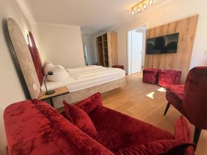 a bedroom with a bed and two red chairs at Spree - Waldhotel Cottbus in Cottbus