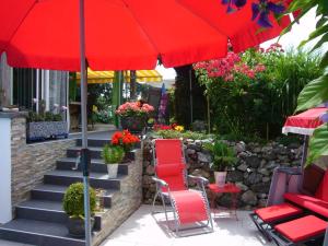 eine Terrasse mit roten Stühlen und einem roten Regenschirm in der Unterkunft Reni's Oase am Bodensee in Kesswil