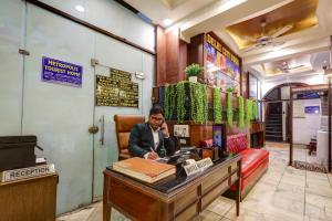 a man sitting at a desk talking on a phone at Hotel The Metropolis Tourist Near Connaught Place And Ramakrishna Ashram Marg Metro Station in New Delhi