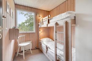 a bunk bed in a room with a window and a chair at Søndervang 4 in Nørre Nebel